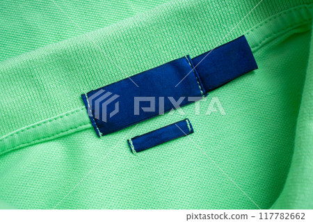 Blank blue laundry care clothes label on green shirt fabric texture background Blank blue laundry care clothes label on green shirt fabric texture background 117782662