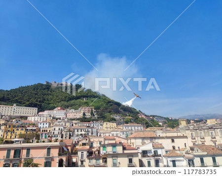 Waterbomber Canadair amphibious seaplane working on extinguishing a hill fire dropping water on the flames 117783735