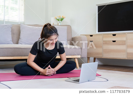 Focused Woman Meditating with Laptop at Home 117783879