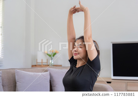 Tranquil Woman Stretching Arms in Home Yoga Practice 117783881
