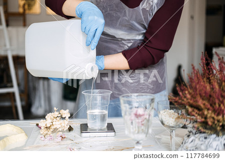 Artisan pouring resin mixture in creative workspace. DIY home decor, floral preservation, handmade crafts, sustainable projects, resin art, artistic process, eco-friendly design. Artisan pouring resin mixture in creative workspace. DIY home decor, floral preservation, handmade crafts, sustainable projects, resin art, artistic process, eco-friendly design. 117784699