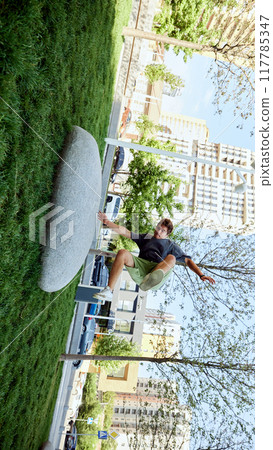 Jumping over large stone, young sportive man showing athletic agility,performing dynamic moves during parkour training in public park Jumping over large stone, young sportive man showing athletic agility,performing dynamic moves during parkour training in public park 117785347