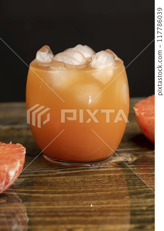 freshly squeezed juice in a glass and ripe red grapefruit on a black table freshly squeezed juice in a glass and ripe red grapefruit on a black table 117786039