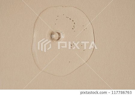 A drop of serum with bubbles on a beige nude background. A drop of serum with bubbles on a beige nude background. 117786763