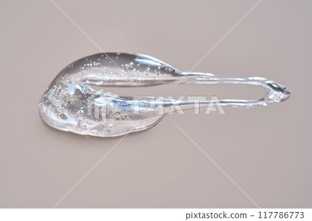 A drop of lubricant or cosmetic gel on a dusty pink background. A drop of lubricant or cosmetic gel on a dusty pink background. 117786773