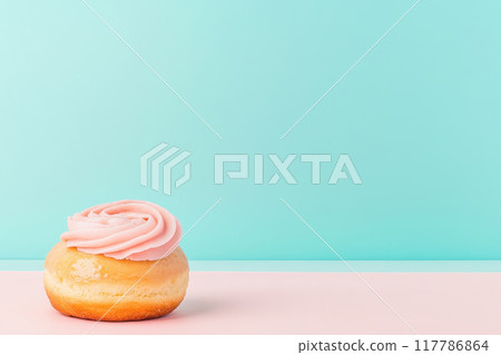 Delicious donut with pink frosting on a pastel background, perfect for sweet treat concepts and dessert imagery. 117786864
