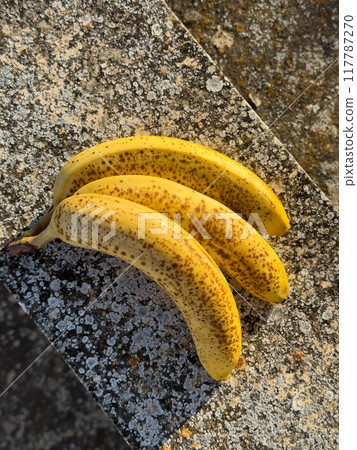 Ripe organic bananas on concrete textured background in sunny day Ripe organic bananas on concrete textured background in sunny day 117787270
