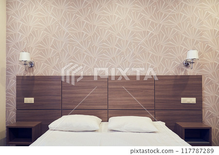 An empty white bed with pillows. The concept of clean bed linen. A place for your design. A sleeping place with pillows and a blanket. With the ability to copy. High quality photo 117787289