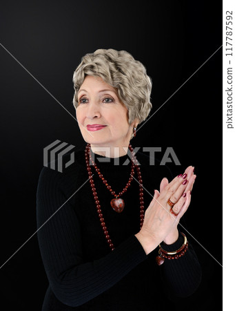 Defying Age with Grace: 76-Year-Old Beauty Icon Dazzles in Red Stone Accessories and Classic Black Attire. 117787592