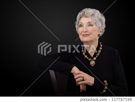 Timeless Charm: Radiant Older Model Exudes Confidence in Black Dress and Leopard Jasper for Striking Senior Portrait. 117787599