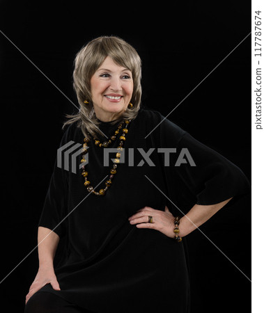 From Darkness to Light: Senior's Radiant Smile and Tiger Eye Accessories Shine in Inspiring Black-Backdrop Portrait. 117787674