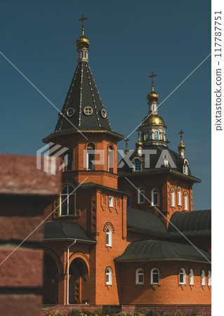 A brick church in the distance, behind a brick pillar 117787751