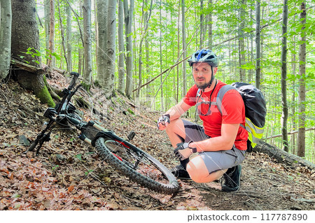 Portrait of man pumping bicycle wheel. Cyclist inflates bicycle wheel using pump. Pumping air into an empty wheel of bike. Portrait of man pumping bicycle wheel. Cyclist inflates bicycle wheel using pump. Pumping air into an empty wheel of bike. 117787890