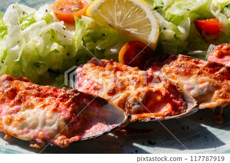 baked mussels with masago caviar and cheese on a white plate 117787919