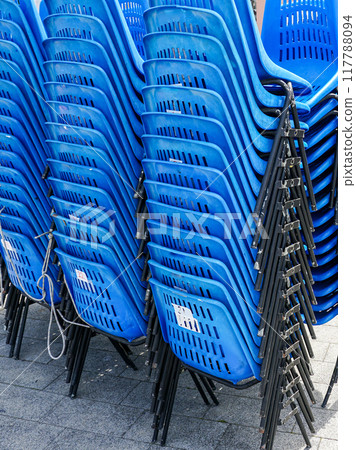Stacked rows of blue plastic chairs with metal frames for outdoor events on town square Stacked rows of blue plastic chairs with metal frames for outdoor events on town square 117788094