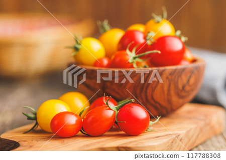 Different colorful cherry tomatoes on wooden cutting board. 117788308