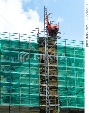 House facade renovation using prefabricated metal tube scaffolding covered with green safety net 117788687