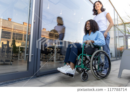 Young woman carrying a wheelchair with a disabled african american woman 117788714