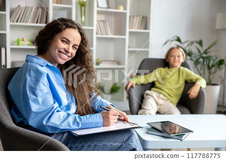 Long-haired female speech therapist working with a hard child and trying to make him feel comfortable Long-haired female speech therapist working with a hard child and trying to make him feel comfortable 117788775