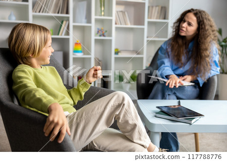 Long-haired female speech therapist working with a hard child and trying to make him feel comfortable 117788776