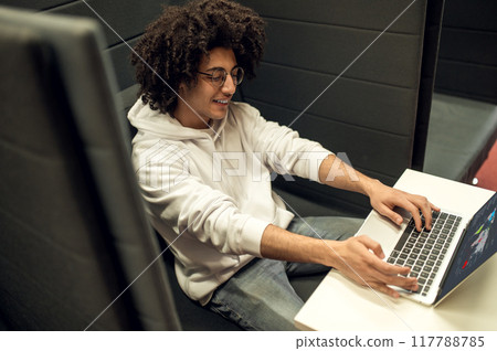 Young male student using laptop for remote studying preparing for seminars in library Young male student using laptop for remote studying preparing for seminars in library 117788785