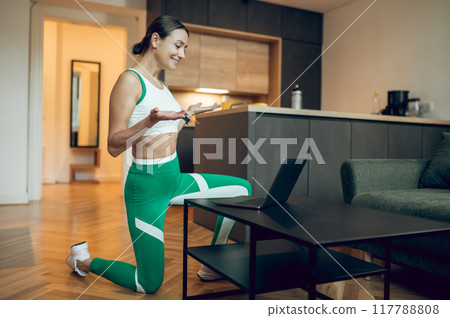 Female fitness coach having online class talking with her client via laptop in home interior Female fitness coach having online class talking with her client via laptop in home interior 117788808