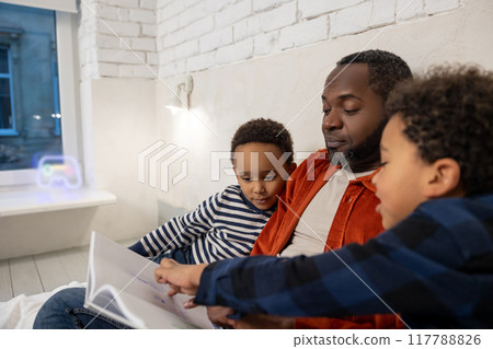 Father and kids reading stories before sleep and looking interested Father and kids reading stories before sleep and looking interested 117788826