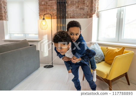 Playful cheerful children wearing denim clothing playing piggybacking Playful cheerful children wearing denim clothing playing piggybacking 117788893