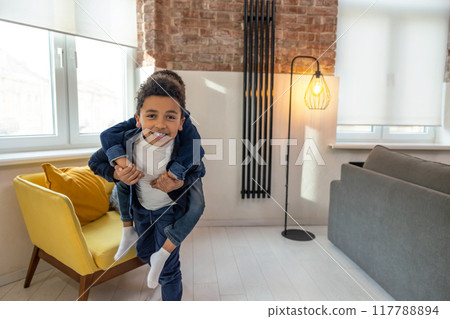 Cheerful African American brothers siblings having fun piggybacking Cheerful African American brothers siblings having fun piggybacking 117788894