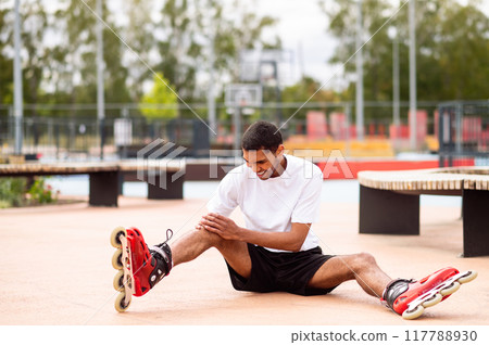Young man learning riding the rollers and laughing while falling down 117788930