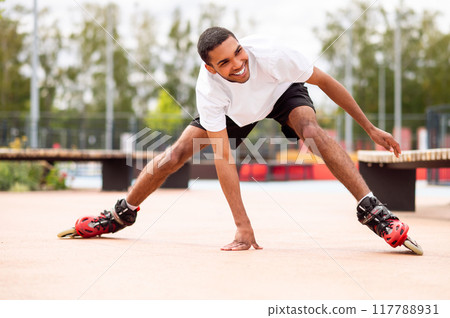 Young man learning riding the rollers and laughing while falling down Young man learning riding the rollers and laughing while falling down 117788931