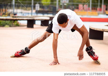 Young man on rollers trying to keep balance and starting to fall down Young man on rollers trying to keep balance and starting to fall down 117788935