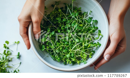 Hands holding a ceramic bowl with microgreens on a white background. Healthy eating, sustainable lifestyle. 117789267