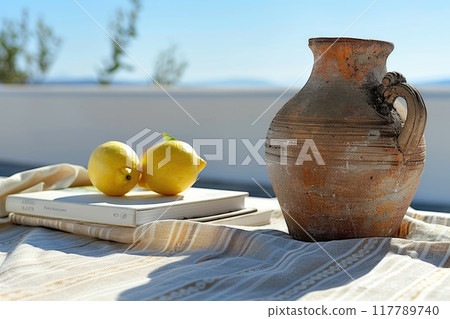 A vase with lemons and a book on a table, surrounded by natural elements 117789740