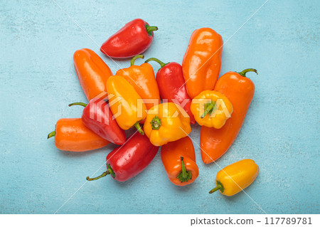 Sweet mini peppers lying on a blue tabletop 117789781