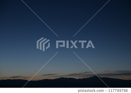 A very thin moon on the eve of the new moon over the Okuchichibu mountain range, seen from Hakushu Town, Hokuto City 117789786