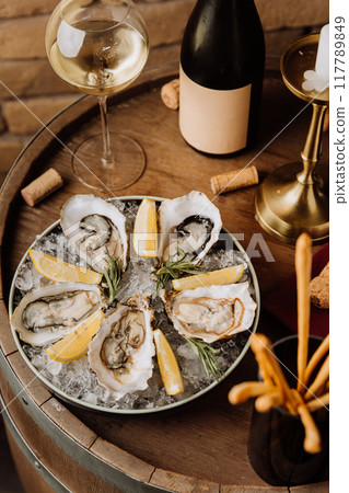 Elegant oysters on ice with lemon and white wine, perfect for gourmet dining and special occasions Elegant oysters on ice with lemon and white wine, perfect for gourmet dining and special occasions 117789849