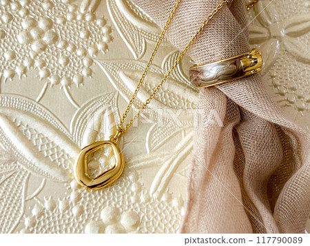 Jewelry photo of gold necklaces and rings elegantly reflected in light on a beautiful woven background 117790089