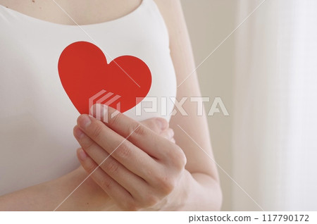 一個女人在胸前拿著一個心形物體 117790172