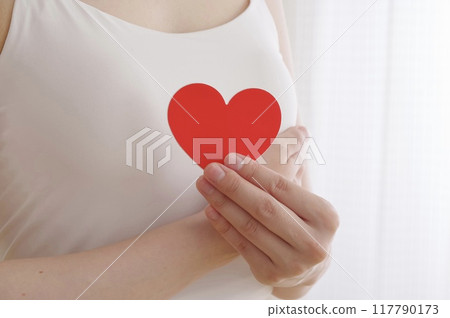 A woman holding a heart-shaped object in front of her chest A woman holding a heart-shaped object in front of her chest 117790173