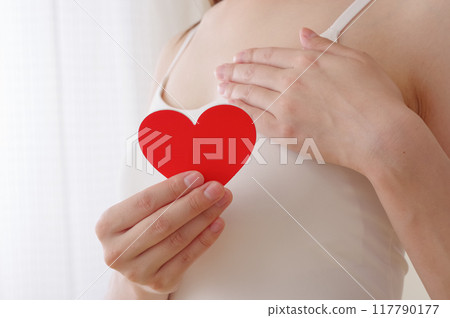 一個女人在胸前拿著一個心形物體 一個女人在胸前拿著一個心形物體 117790177