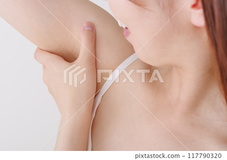 Image of a woman removing unwanted armpit hair 117790320