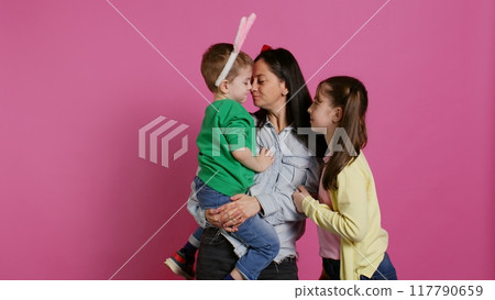 Adorable lovely family showing love and laughing on camera, children feeling happy and playful in studio. Mother with a boy and a girl kissing and hugging each other, joyful people. Camera B. Adorable lovely family showing love and laughing on camera, children feeling happy and playful in studio. Mother with a boy and a girl kissing and hugging each other, joyful people. Camera B. 117790659
