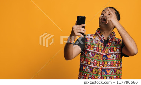 Happy man chatting with friend over online videocall on smartphone, doing friendly gestures. Smiling person communicating with mate on teleconference using mobile phone, studio background, camera A Happy man chatting with friend over online videocall on smartphone, doing friendly gestures. Smiling person communicating with mate on teleconference using mobile phone, studio background, camera A 117790660