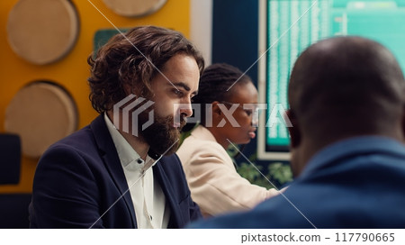Team of associates working on resource allocation plans during a meeting, making important budgeting and staffing decisions to corelate with company objectives. Employees review strategies. Camera A. 117790665