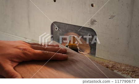 Woodworker operating spindle moulder to create high quality bespoke joinery for customer commissioned project. Machinist at work performing tasks on wood shaper, shaping materials, camera B close up 117790677