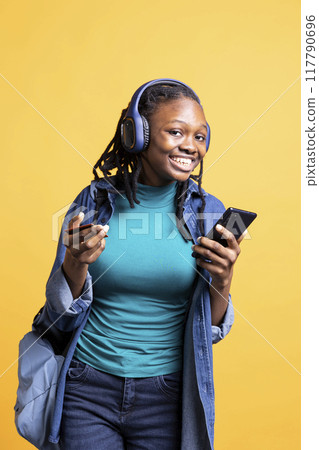 Portrait of cheerful woman adding payment method on website, enjoying promotions, isolated over studio background. Jolly young girl does internet shopping, typing credit card information on cellphone 117790696