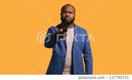 Sports fan watching in disbelief match broadcast after own team fails to score, ready to switch channel. Man frustrated with favorite club after committing blunder, studio background, camera B Sports fan watching in disbelief match broadcast after own team fails to score, ready to switch channel. Man frustrated with favorite club after committing blunder, studio background, camera B 117790715