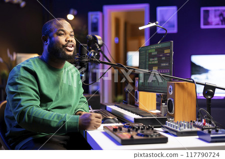 African american composer writing a new song with romantic verses, thinking of melodic elements to blend together. Artist songwriter composing a track, making rhymes with lyrics. 117790724