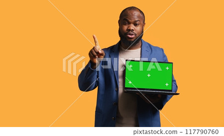 Upset african american man shows thumbs down sign gesturing holding green screen laptop, disapproving. Reviewer does rejection hand gesture regarding chroma key notebook, studio background, camera B Upset african american man shows thumbs down sign gesturing holding green screen laptop, disapproving. Reviewer does rejection hand gesture regarding chroma key notebook, studio background, camera B 117790760